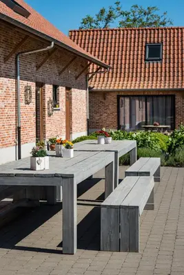 a picnic table and benches in front of a building at Vakantiehoeve Berckelaer in Sint-Gillis-Waas