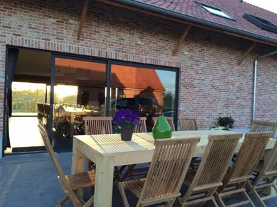 a wooden table and chairs on a patio at Vakantiehoeve Berckelaer in Sint-Gillis-Waas
