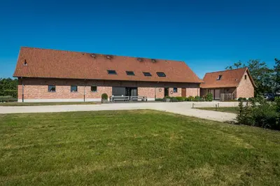 a large brick building with a bench in front of it at Vakantiehoeve Berckelaer in Sint-Gillis-Waas