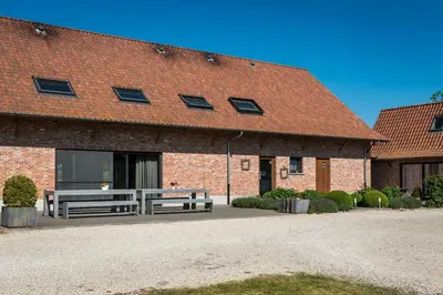 a brick building with two benches in front of it at Vakantiehoeve Berckelaer in Sint-Gillis-Waas