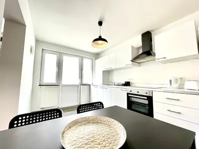 a kitchen with white cabinets and a black table and chairs at COSY Duplex - EU DISTRICT in Brussels