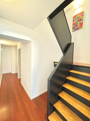 a black staircase in a white room with wooden floors at COSY Duplex - EU DISTRICT in Brussels