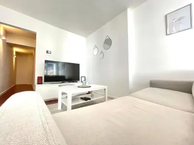 a white room with two beds and a tv at COSY Duplex - EU DISTRICT in Brussels