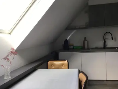 a kitchen with a table and two chairs and a window at Cosy attic apartment, terrace, 1 bedroom, double bed for 2 plus single bed if 3 guests in Buggenhout