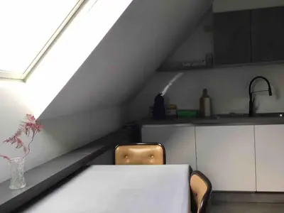 a table and chairs in a kitchen with a window at Cosy attic apartment, terrace, 1 bedroom south, 1 double bed for 2, plus single bed if 3 guests in Opdorp