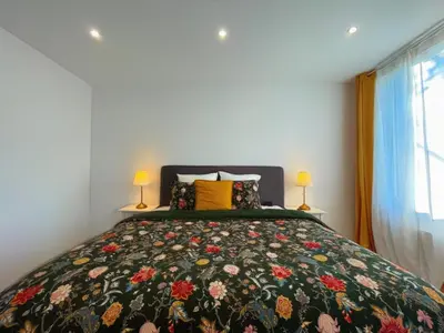 a bedroom with a bed with a floral bedspread at La Perla Appartements in Brussels
