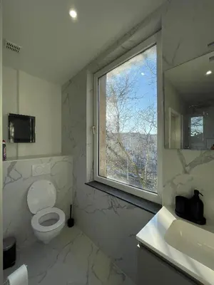 a bathroom with a window and a toilet and a sink at La Perla Appartements in Brussels