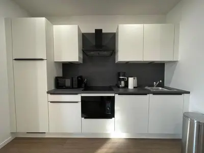 a kitchen with white cabinets and a sink at La Perla Appartements in Brussels