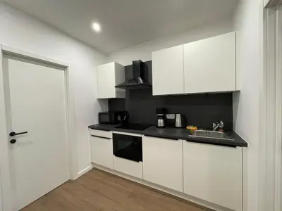 a kitchen with white cabinets and a sink at La Perla Appartements in Brussels