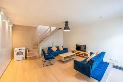 a living room with blue chairs and a staircase at Temse city center in Temse