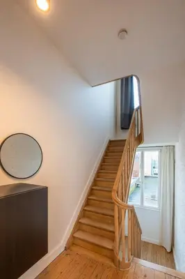 a staircase in a house with white walls and wooden floors at Temse city center in Temse