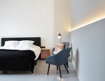 a bedroom with a bed and a chair and a lamp at B&B Ceder10 in Kruibeke