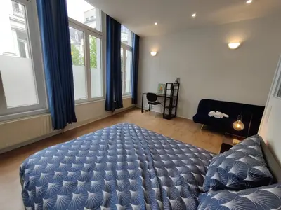 a bedroom with a bed and a couch and windows at Nice Flat Grand Place in Brussels