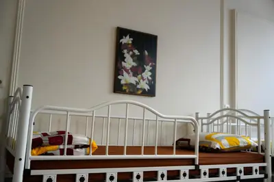 a bedroom with a white bed and a painting on the wall at YOUR HOSTEL midi station in Brussels