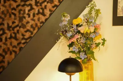 a vase of flowers on a wall next to a lamp at Charming home by Grote Markt with Free Parking in Antwerp