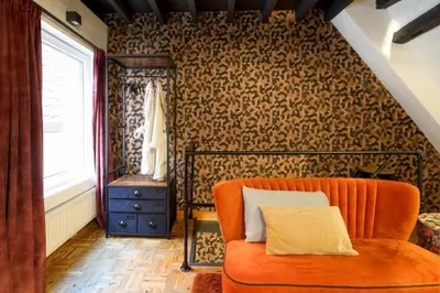 an orange couch in a room with wallpaper at Charming home by Grote Markt with Free Parking in Antwerp