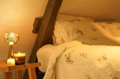 a bed with white sheets and a candle on a table at Charming home by Grote Markt with Free Parking in Antwerp