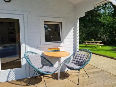 two chairs and a table on the porch of a house at Cozy tiny house with swimming pool & outdoor sauna in Waasmunster