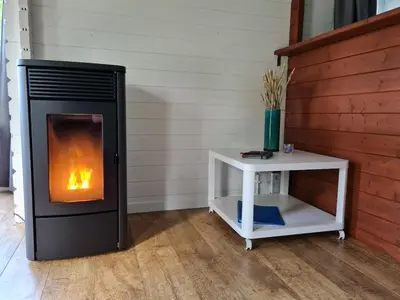 a fireplace in a room with a side table at Cozy tiny house with swimming pool & outdoor sauna in Waasmunster
