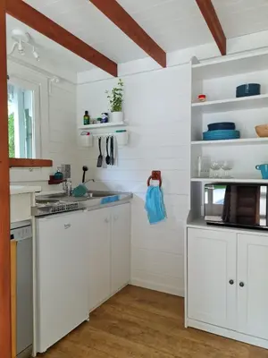 a kitchen with white counters and white cabinets at Cozy tiny house with swimming pool & outdoor sauna in Waasmunster