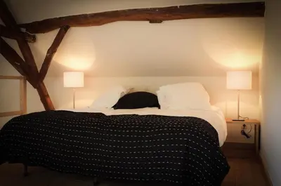 a bed with black and white sheets and two lamps at Geestmolenhof 1 in Holsbeek