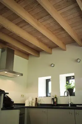 a kitchen with wooden ceilings and black counter tops at Geestmolenhof 1 in Holsbeek