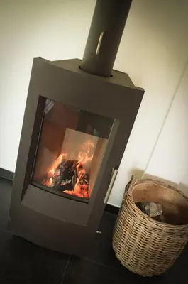 a fireplace with a fire in it next to a basket at Geestmolenhof 1 in Holsbeek