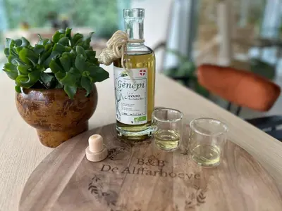 a bottle of alcohol sitting on a table with glasses at B&B De Alffarhoeve in Hamme