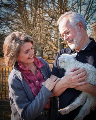 a woman standing next to a man holding a sheep at B&B De Alffarhoeve in Hamme