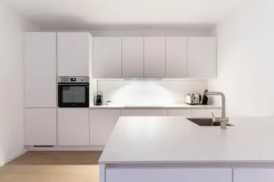 a white kitchen with white cabinets and a sink at Inviting and bright 7-Person Apartment in Antwerp in Antwerp