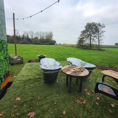 a picnic table and a tub and a table in a field at Kromven Puur Genieten in Merksplas