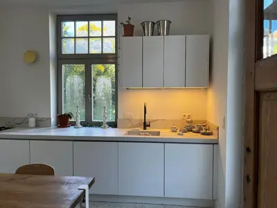 a kitchen with white cabinets and a sink and a window at Superb house in absolute calm in Linkebeek
