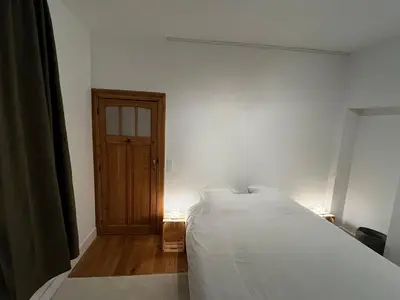 a bedroom with a white bed and a wooden door at Superb house in absolute calm in Linkebeek