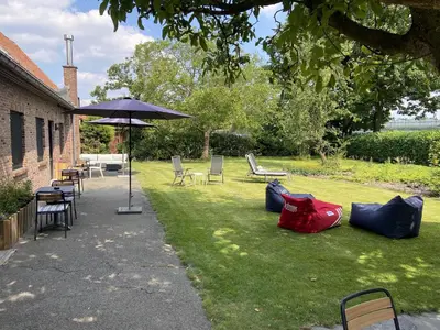 a lawn with chairs and tables and an umbrella at Pop-Up camping close to festival - Ganzendrieshoeve in Rumst