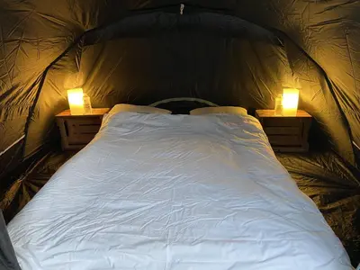 a bed in a tent with two lights on it at Pop-Up camping close to festival - Ganzendrieshoeve in Rumst