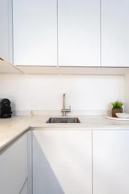 a kitchen with white cabinets and a sink at Comfortable Urban Retreat for 6 in Central Antwerp in Antwerp