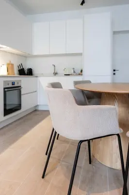 a kitchen with white cabinets and a wooden table and chairs at Modern 6-Guest Apartment in Central Antwerp in Antwerp