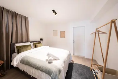 a bedroom with a bed with white sheets at Stylish Duplex for 8 in Central Antwerp in Antwerp