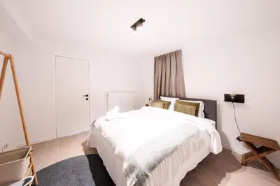 a white bedroom with a large bed and a table at Stylish Duplex for 8 in Central Antwerp in Antwerp