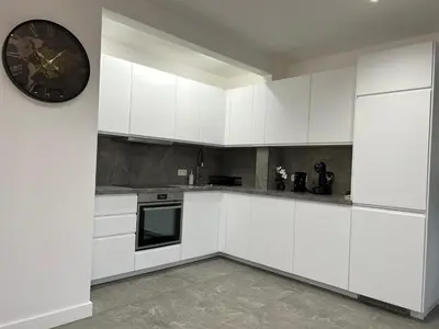 a kitchen with white cabinets and a clock on a wall at Splendide appartement neuf à Zaventem airport in Zaventem