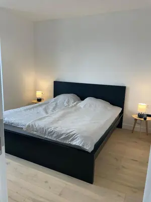 a bed with a black frame and white sheets at Splendide appartement neuf à Zaventem airport in Zaventem