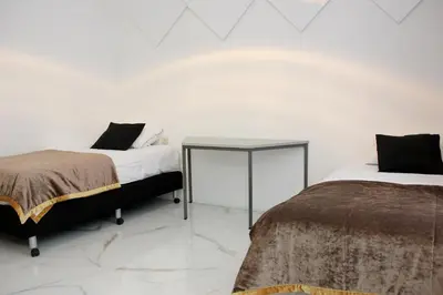 two beds in a white room with a table at Luxury Apartments Arendshof in Antwerp
