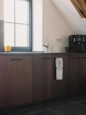 a kitchen with wooden cabinets and a window at Sheela Farm in Rumst