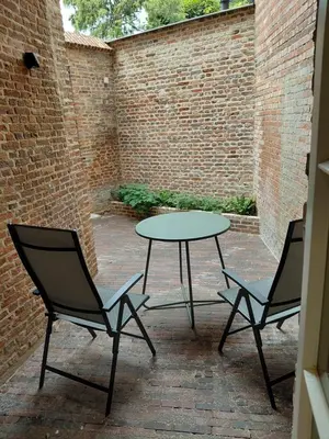 two chairs and a table in a courtyard with a brick wall at Begijnhofpoort B&B in Turnhout