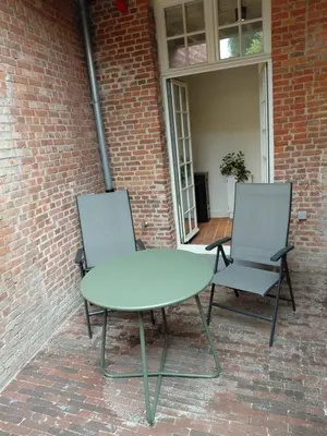 two chairs and a table in front of a brick building at Begijnhofpoort B&B in Turnhout