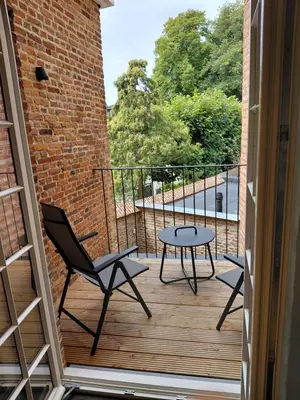 a balcony with a table and chairs and a brick wall at Begijnhofpoort B&B in Turnhout
