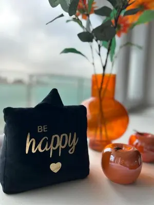 a black pillow with the words be happy next to a vase at Charmant appartement in Antwerpen Zuid met zicht op de stroom in Antwerp
