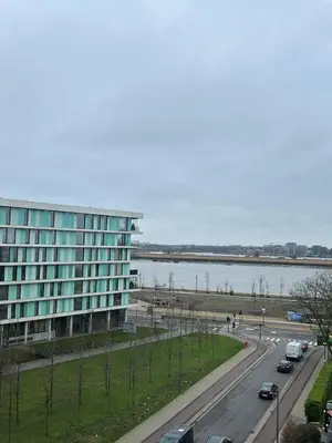 a large building next to a road next to a body of water at Charmant appartement in Antwerpen Zuid met zicht op de stroom in Antwerp
