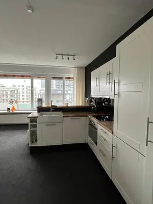 a kitchen with white cabinets and a large window at Charmant appartement in Antwerpen Zuid met zicht op de stroom in Antwerp