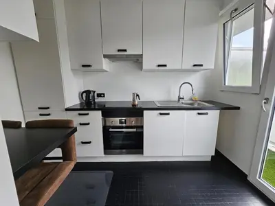 a kitchen with white cabinets and a sink and a window at Studio El - Cozy Bright Flat in the Green Corner of Antwerp in Antwerp